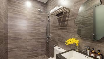 A modern bathroom with a shower, toilet, and sink, featuring a marble wall and a mirror.
