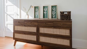 A wooden dresser with woven front panels and three framed botanical designs on top. - Allura Oakland Your Private Sanctuary in the City (Oakland)