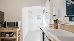 A modern kitchen with white cabinetry, a microwave, a coffee maker, and a dishwasher. - Allura Oakland Your Private Sanctuary in the City (Oakland)