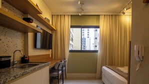 A compact room with a kitchenette, a dining area, and a bed. - 360 Pamplona NR  (São Paulo)