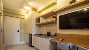A compact kitchen with a microwave, coffee maker, and a TV mounted on the wall. - 360 Pamplona NR  (São Paulo)
