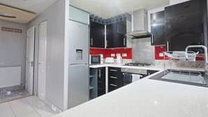 A modern kitchen with white cabinets, a red backsplash, and stainless steel appliances. - Manchester 3-beds, Sleeps 6 With On-site Parking (Manchester)
