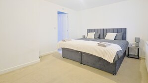 A bedroom with a bed, bedside table, and a door leading to another room. - Manchester 3-beds, Sleeps 6 With On-site Parking (Manchester)