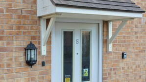 A white door with the number 5, a black lantern, and two warning signs on a brick wall. - Manchester 3-beds, Sleeps 6 With On-site Parking (Manchester)