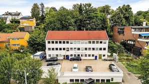 A multi-story building with a red-tiled roof, surrounded by greenery and other buildings. - The Cozy Oslo Stay (Oslo)