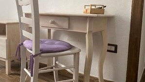 A wooden desk with a white chair that has a purple cushion. - Dani's House - affittacamere (Cagliari)