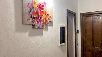 A hallway with a wooden floor, a wall-mounted clock, and a door.