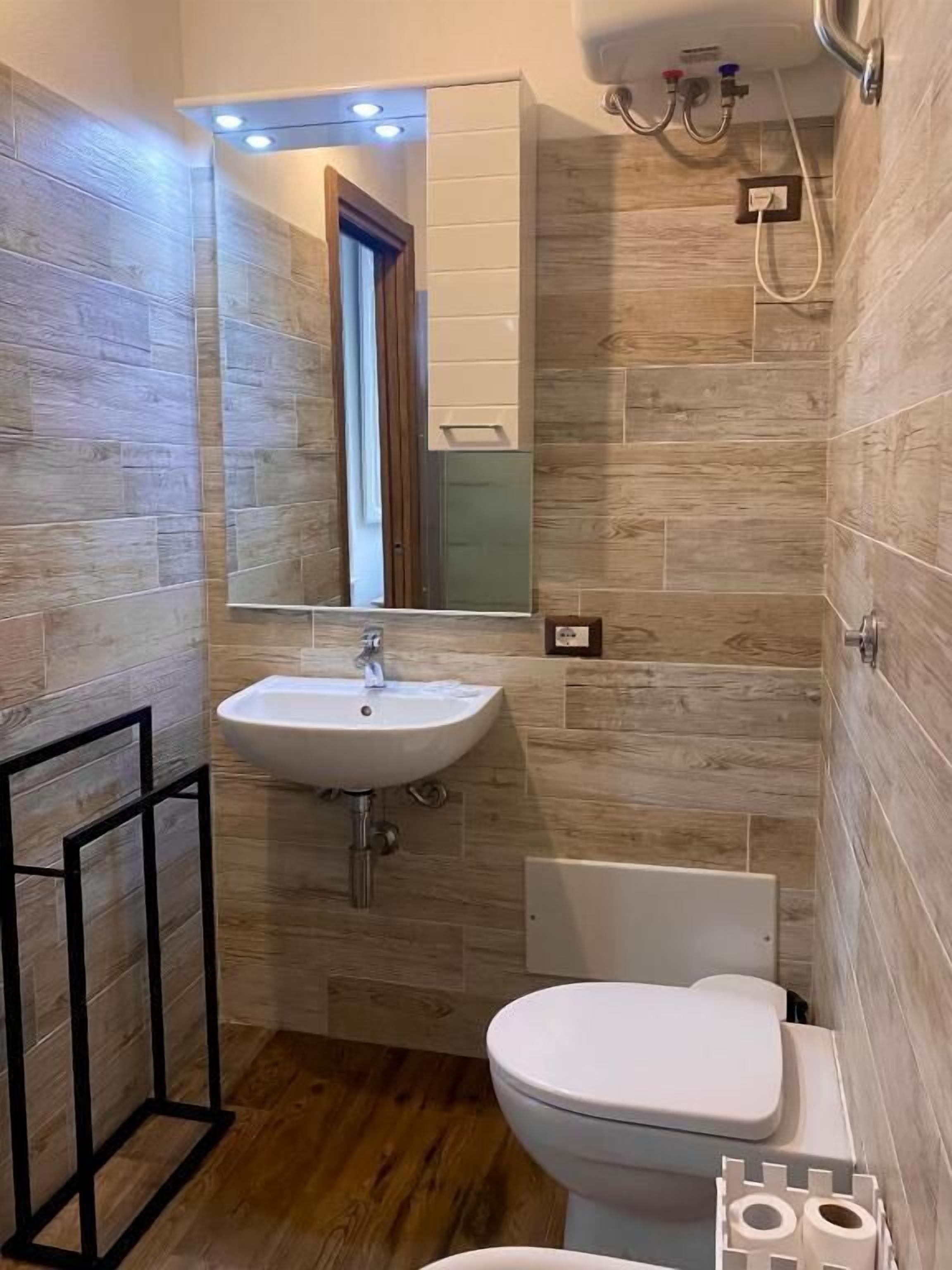 A compact bathroom with a white sink, a toilet, and a shower area.