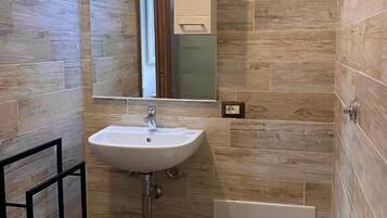 A compact bathroom with a white sink, a toilet, and a shower area.