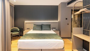 Ett modernt hotellrum med en stor säng, ett sängbord, en stol och en inbyggd garderob.