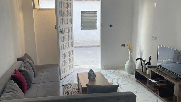 A modern living room with a grey sofa, a wooden coffee table, and a TV on a wooden stand. - House of la Marsa (La Marsa)