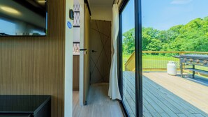 Un couloir doté d’un plancher en bois mène à un balcon équipé d’un barbecue et d’une bouteille de gaz.