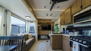 Une cuisine compacte pour camping-car, équipée d’une cuisinière, d’un four et d’un coin repas avec une banquette.