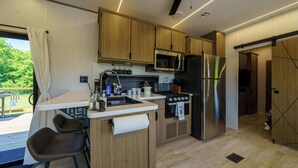 Une cuisine moderne avec des meubles en bois, un réfrigérateur en acier inoxydable, un four à micro-ondes et une cuisinière à gaz.