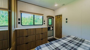 Une chambre à coucher avec un lit, une commode, une fenêtre et une porte.
