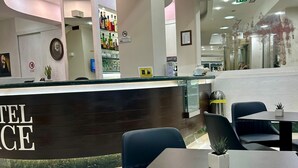 A hotel reception area with a curved counter, seating, and a bar. - Hotel Pace (San Giovanni Rotondo)