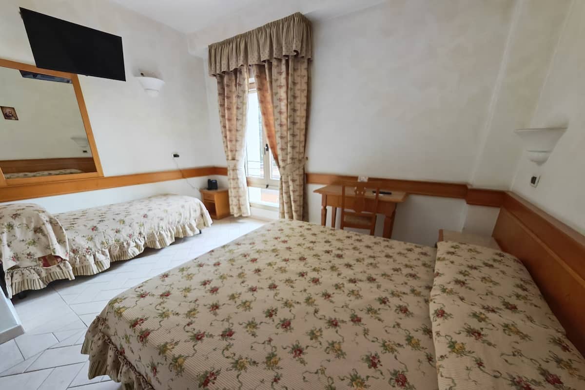 A hotel room with two beds, a desk, and a chair.