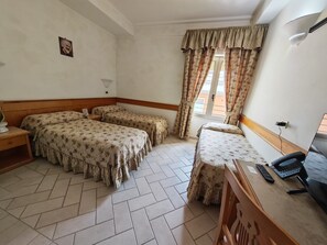 A hotel room with two beds, a desk with a computer, a lamp, and a window with curtains. - Hotel Pace (San Giovanni Rotondo)