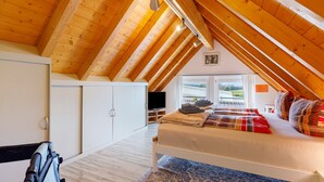 A bedroom with a sloped ceiling, a bed with a blanket, pillows, a TV, and a window. - Apartment 'Ferienwohnung am Rosenberg' with Shared Garden, Wi-Fi and Air Conditioning (Stockach)
