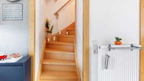 A wooden staircase with a handrail, a clock, a sign with German text, and a radiator. - Apartment 'Ferienwohnung am Rosenberg' with Shared Garden, Wi-Fi and Air Conditioning (Stockach)