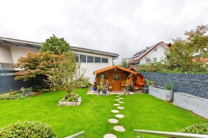 Una casa moderna con césped cuidado, un camino de piedra y una terraza de madera.