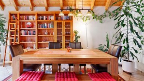 A wooden dining table with red cushions, surrounded by bookshelves and chairs. - Apartment 'Ferienwohnung am Rosenberg' with Shared Garden, Wi-Fi and Air Conditioning (Stockach)