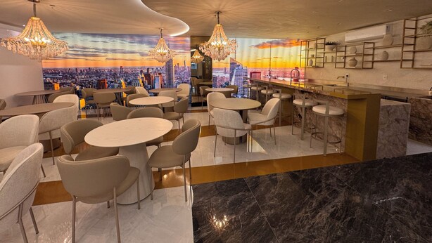 A modern bar area with round tables and chairs, a cityscape mural on the wall, and a sign indicating an exit.