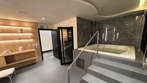 A modern bathroom with a marble wall, a bathtub, and a wooden vanity.