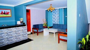 Una sala moderna con una pared azul decorativa, un mostrador de recepción, un conjunto de sofás y una mesa de centro.