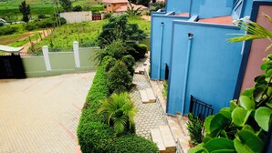 Una zona residencial con un sendero pavimentado, un edificio azul y un paisaje verde al fondo.