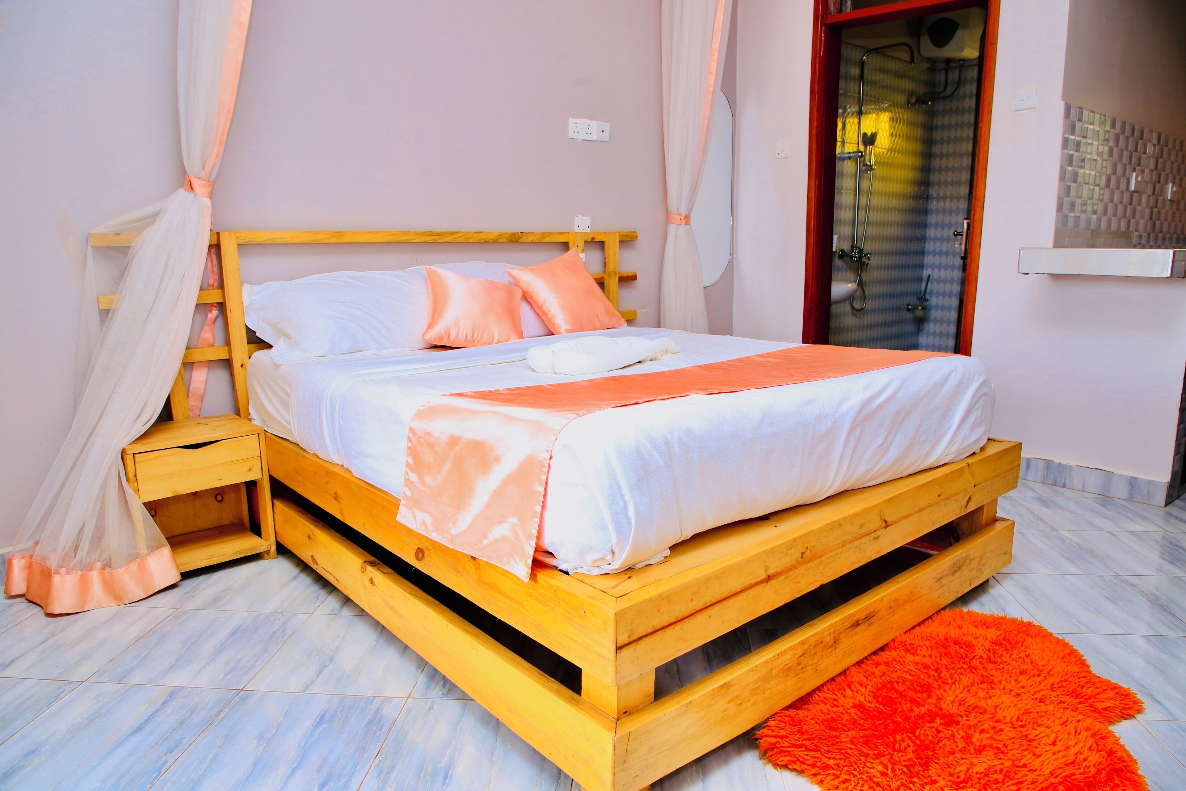 A bed with a wooden frame, white bedding, and orange accents.