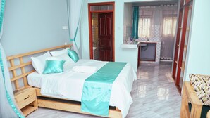 Un dormitorio con cama y mesita de noche de madera, un baño con lavabo y espejo, y vistas al exterior.