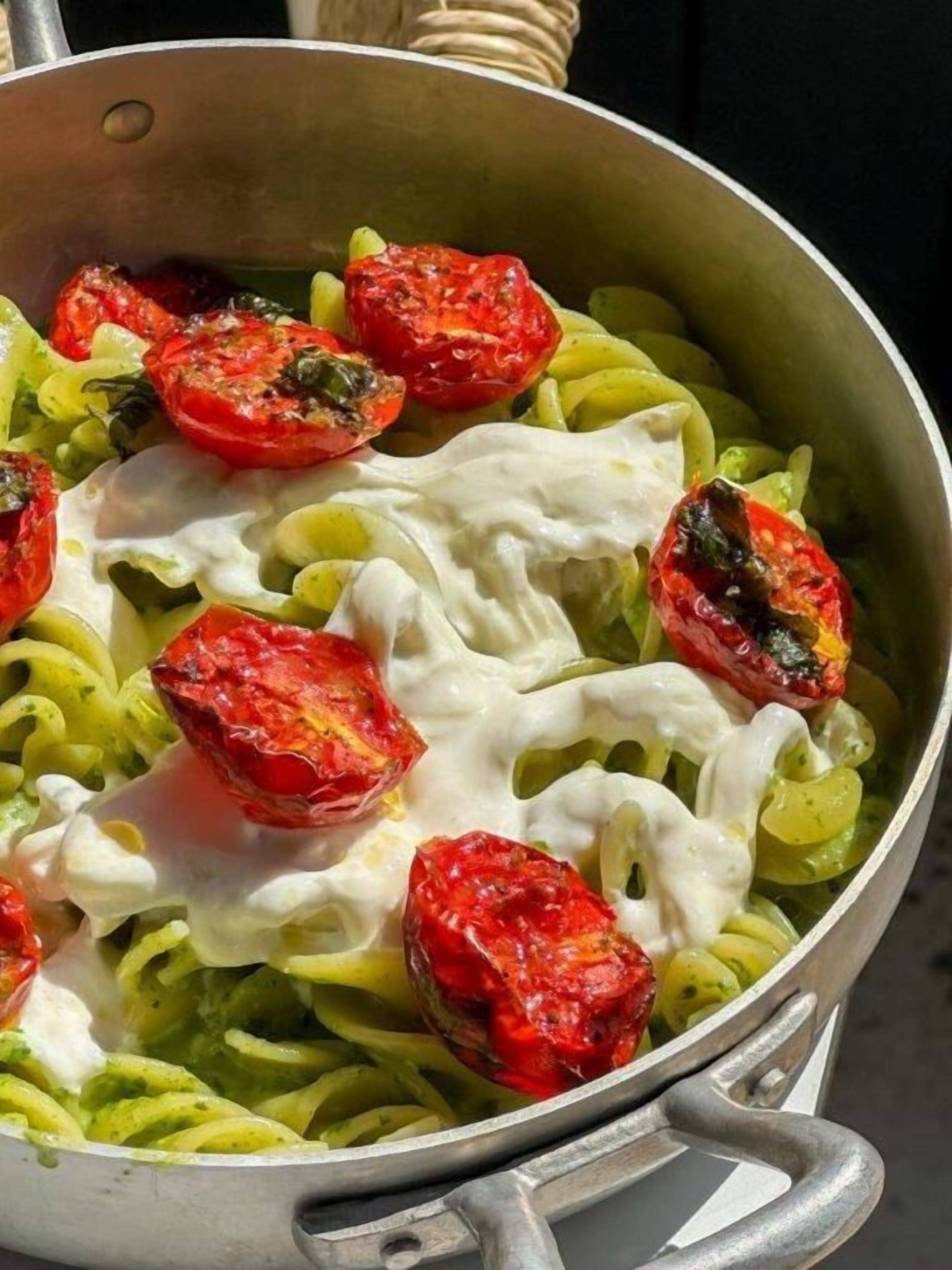 A pot of pasta with cherry tomatoes and a creamy sauce.