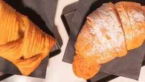 Two croissants on black napkins on a table with a cup of coffee. - EXTRA B&B (Trani)