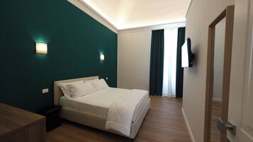 A bedroom with a bed, a nightstand, a TV mounted on the wall, and a door.