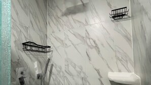 Ein Badezimmer mit Marmorwänden, einer Duschkabine und zwei schwarzen Handtuchhaltern.