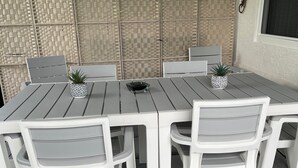 Eine Terrasse mit Tisch und Stühlen, einem Deckenventilator und einer Zierwand.