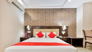 Habitació d'hotel amb un llit gran, dues taules de nit, una cadira i una paret decorativa.