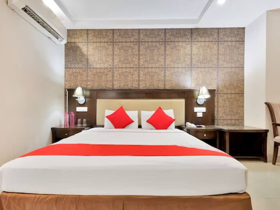 A hotel room with a large bed, two bedside tables, a chair, and a decorative wall.