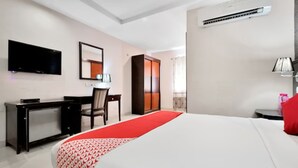 Una habitació d'hotel amb llit, escriptori, cadira, televisió, armari i aire condicionat.