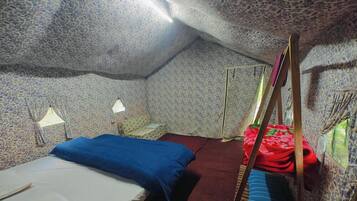 A small, cozy room with a single bed, a nightstand, a lamp, and a window with a view.