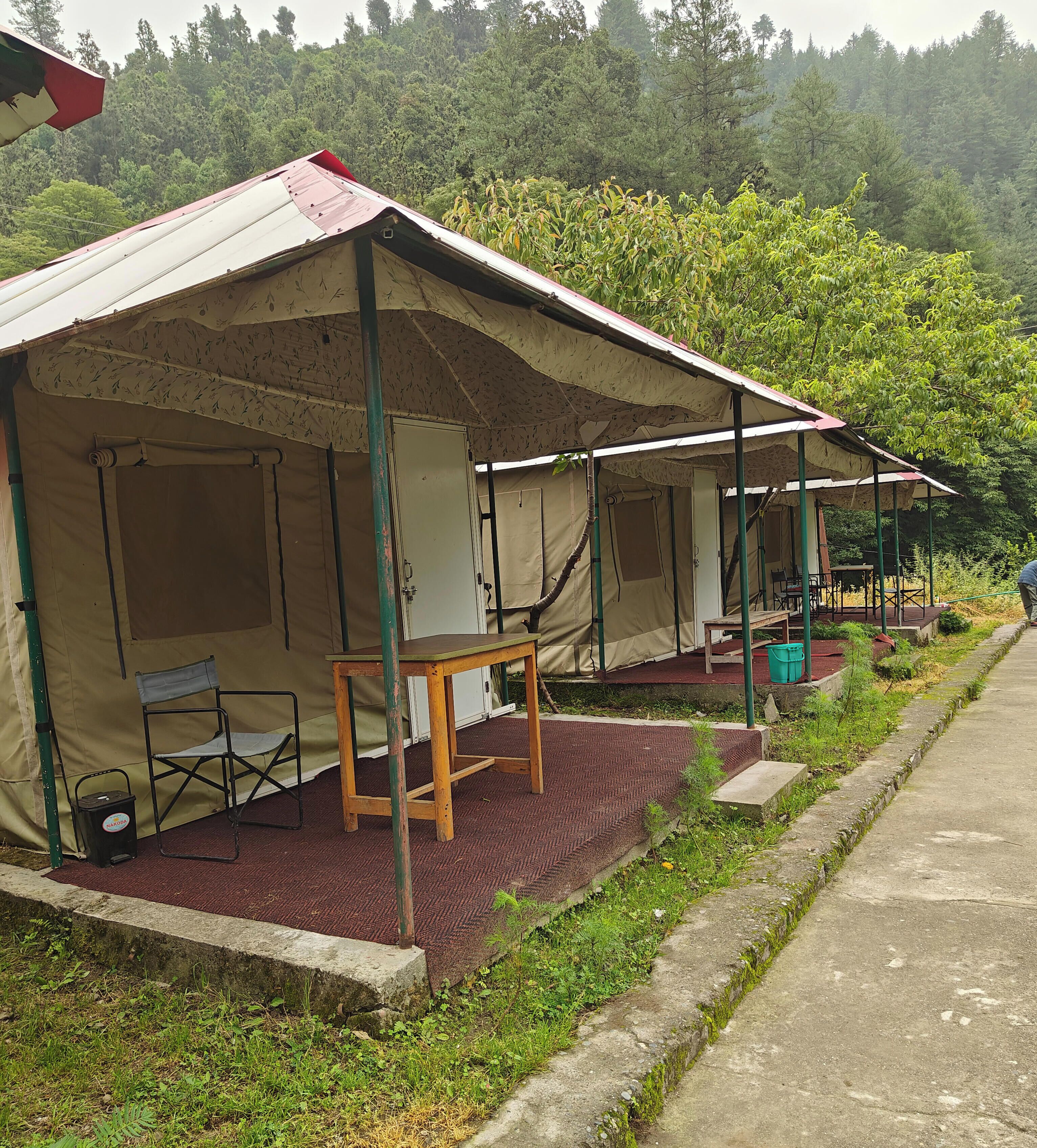 A campsite with tents, a table, chairs, and a portable stove.