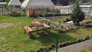 Un terrain de camping avec deux tentes blanches, des tables de pique-nique et une rivière en arrière-plan.
