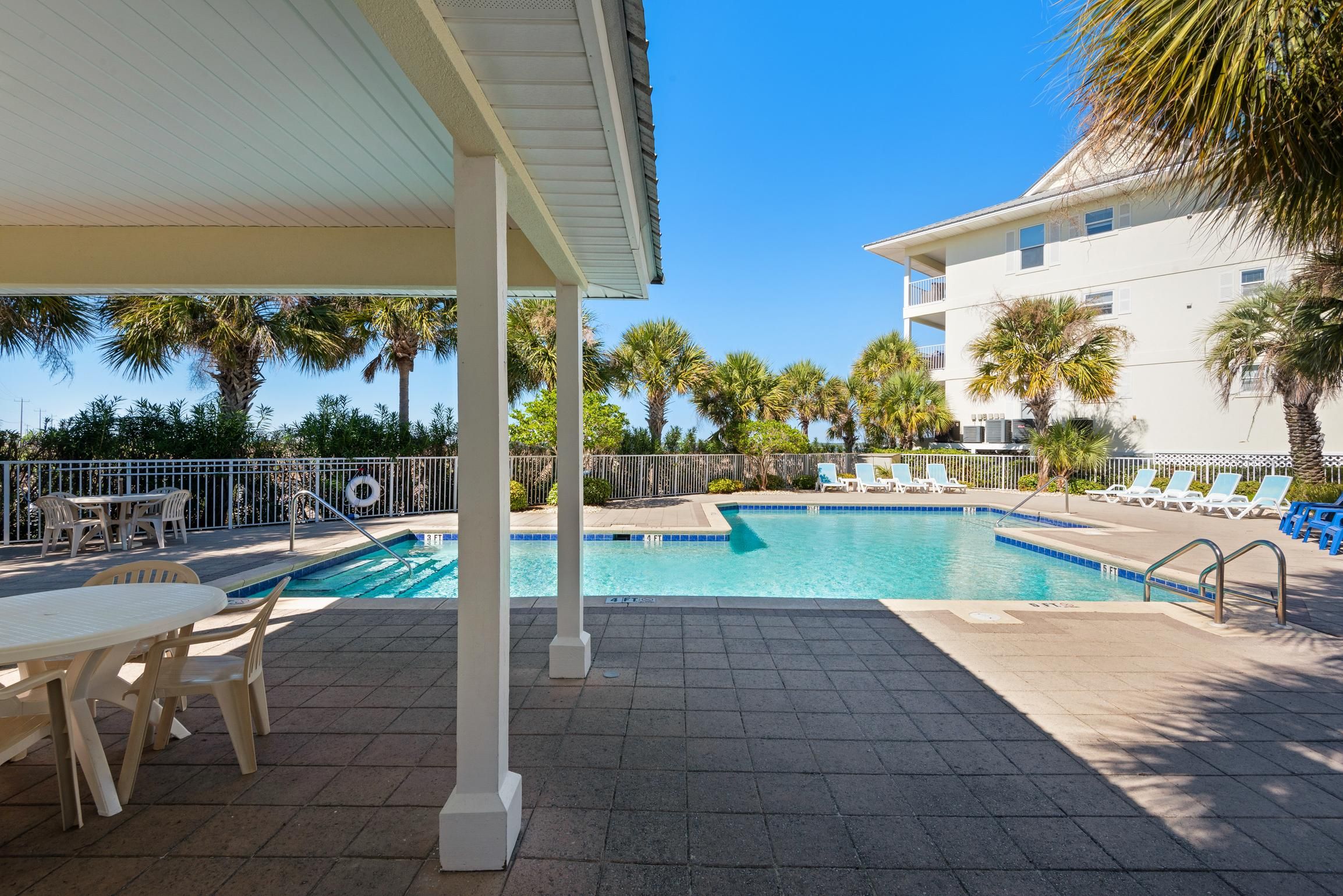 A pool area with lounge chairs and a covered seating area.