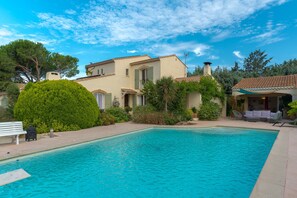 A swimming pool with a patio area, a building with a tiled roof, and surrounding greenery. - Apartment 'Havre De Paix' with Shared Pool, Wi-Fi and Air Conditioning (Salon-de-Provence)