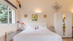 Un dormitorio con cama, armario, radiador, ventana y decoración en la pared.