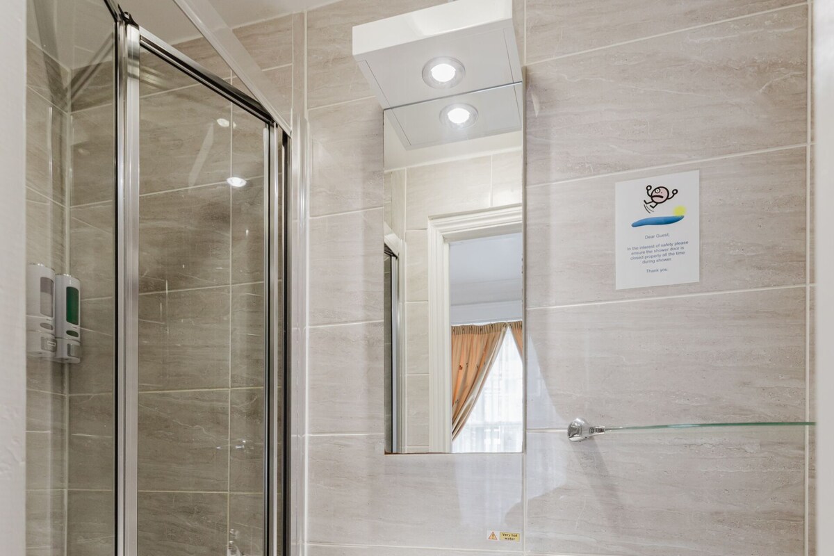 A modern bathroom with a glass shower enclosure, a white sink, and a mirror above it.
