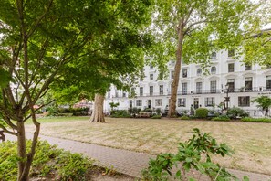 A white building with multiple windows and balconies, surrounded by trees and a paved area. - Falcon Hotel (London)