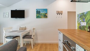 Una cocina moderna con encimera de madera, horno empotrado y televisor montado en la pared.