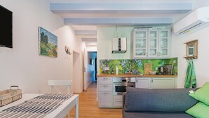 Un espacio habitable compacto con kitchenette, comedor y zona de estar.